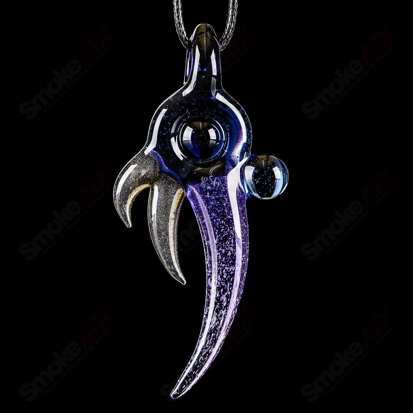 Dosh Glass amulet pendant featuring a colorful glass design, hanging from a metal chain on a neutral background.