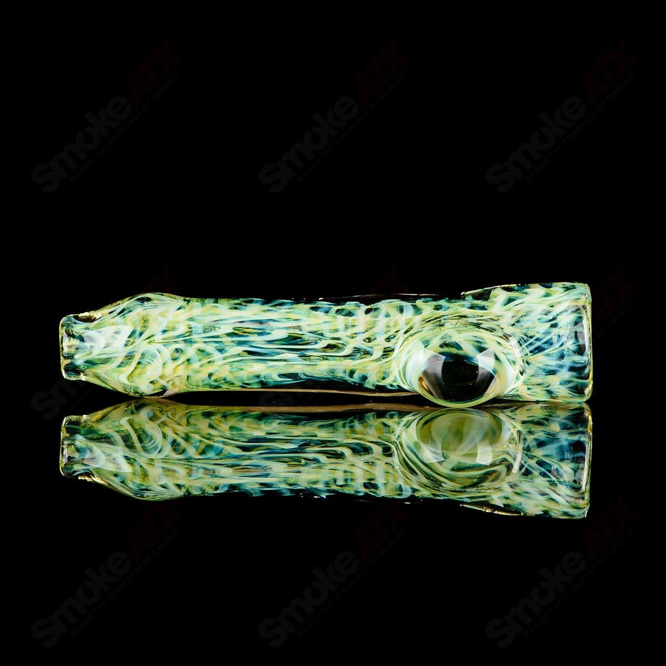 Glass chillum with signed JMK Glass logo and intricate worked design, showcasing clear glass craftsmanship.
