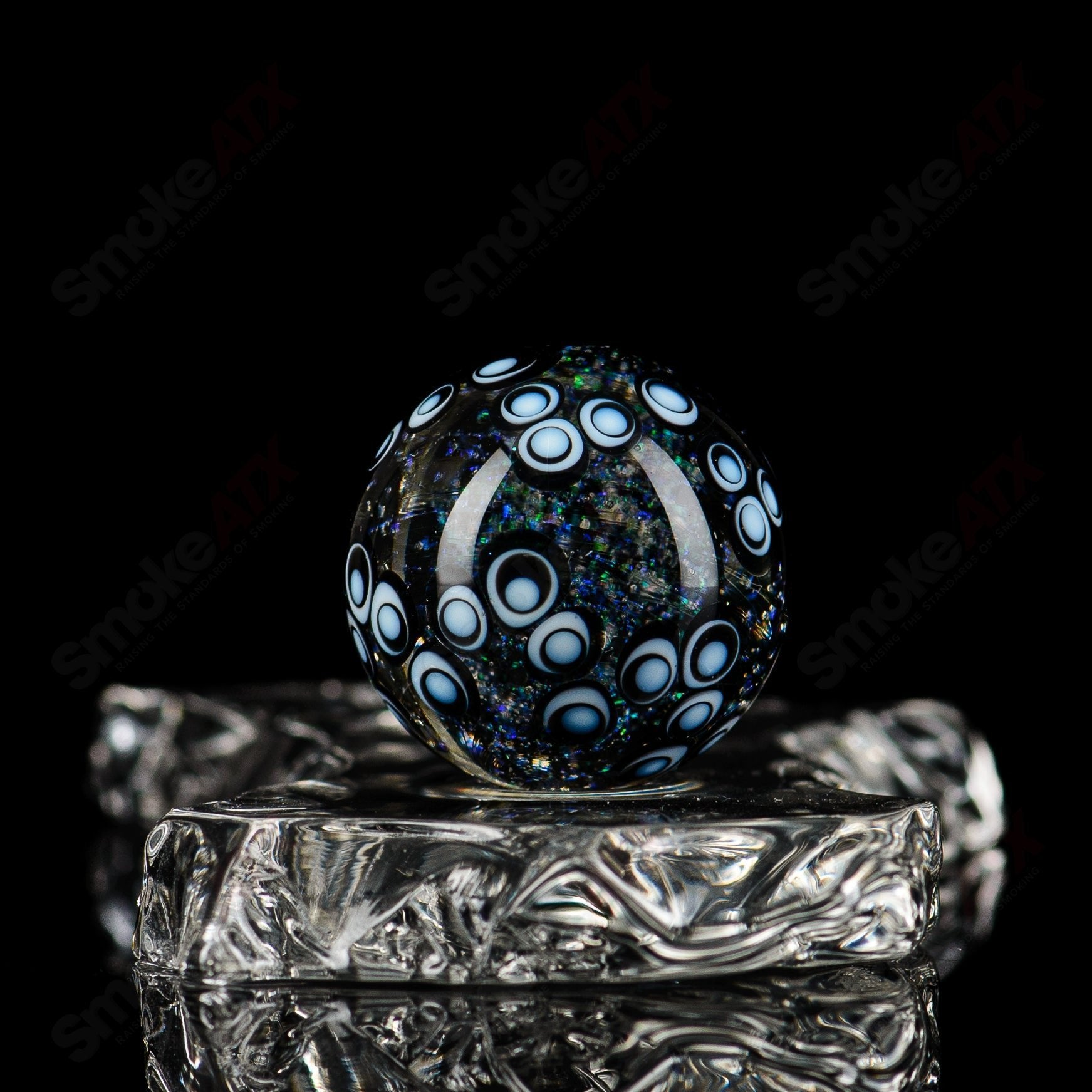Clear glass marbles with a caged dot stack design by Indo Glass, featuring smooth, rounded surfaces and intricate pattern details.