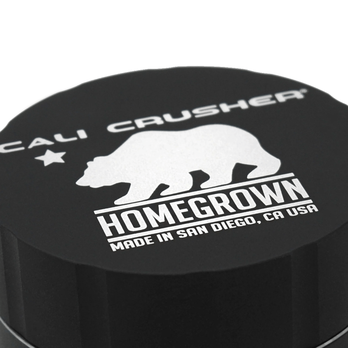 Cali Crusher 4-piece Homegrown Black metal grinder with sharp teeth and magnetic top for herb grinding and collection.
