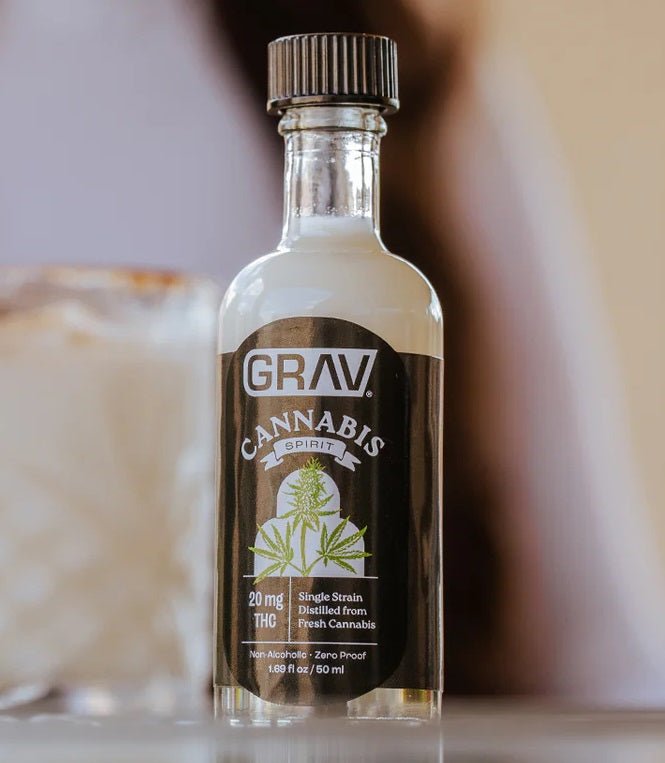 Bottle of GRAV Cannabis Spirit hemp THC drink with label showing cannabis leaf and branding, on a wooden surface.