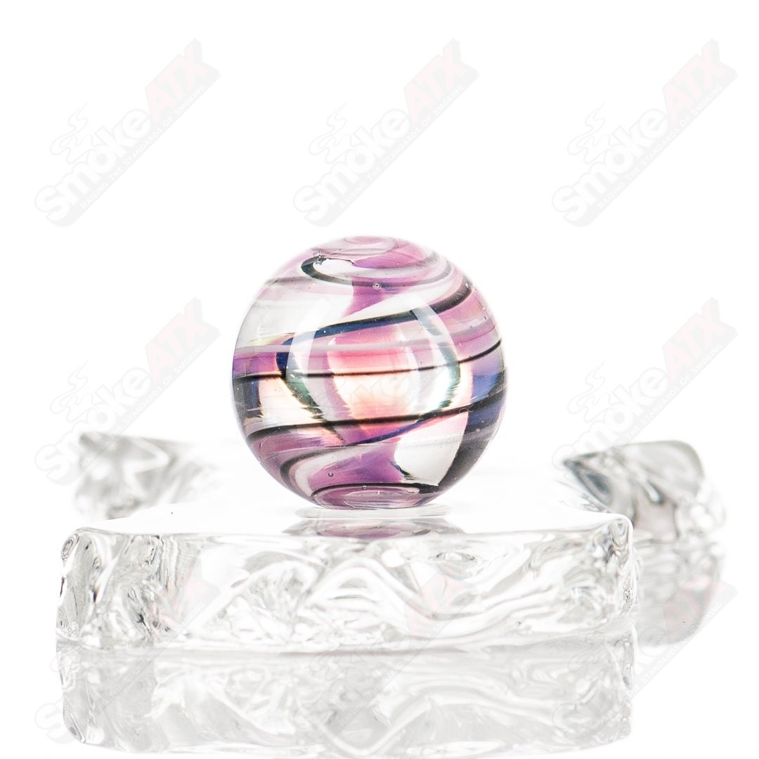 Colorful UV spiral marble by Indo Glass, made of glass, showcasing vibrant swirling patterns on a smooth, rounded surface.