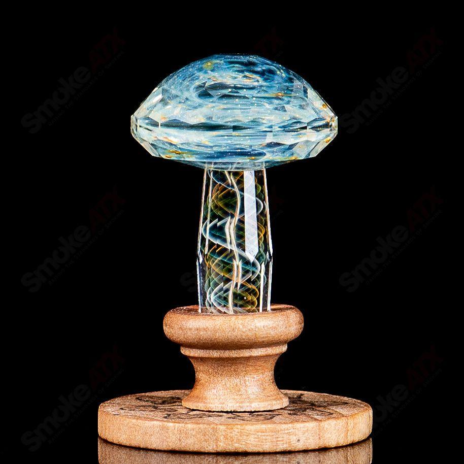 Faceted Ghost Filigrana Mushroom by Fatal Facets on a wooden stand, showcasing vibrant glass artistry and intricate design details.