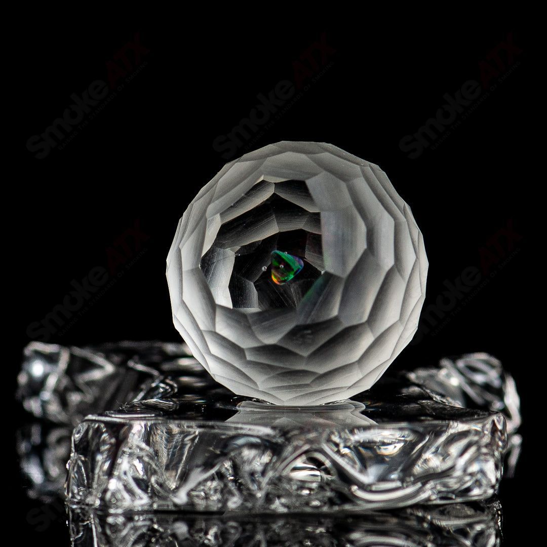 Faceted marble from Fatal Facets made of glass with a smooth, polished surface and intricate faceted design.