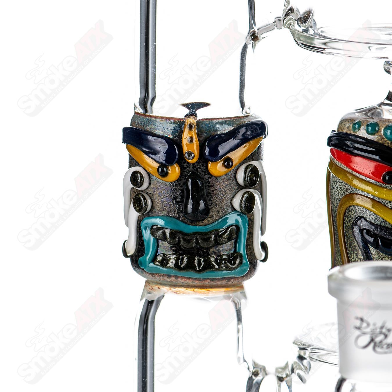 Spinning Tiki Head Scientific Tube by Carsten Carlile and Dirty Rico Glass, featuring detailed tiki face design and clear glass construction.