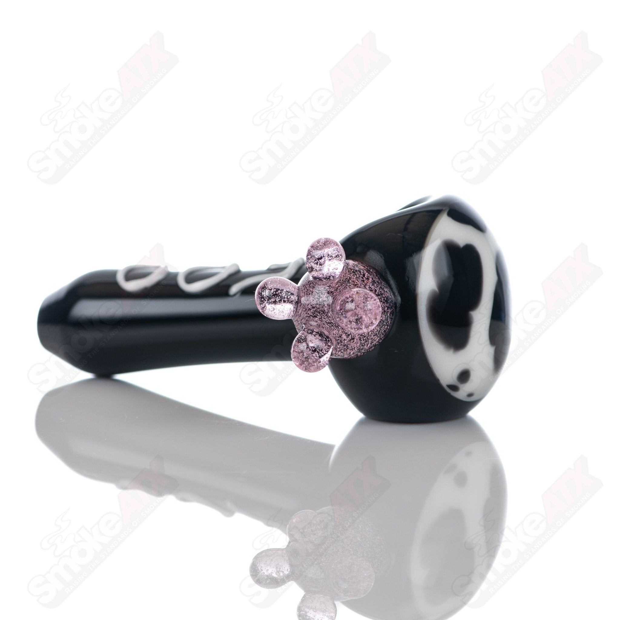 Black cow print glass spoon pipe by Adventures In Glass Blowing, showcasing a detailed black and white cow pattern on a smooth pipe.