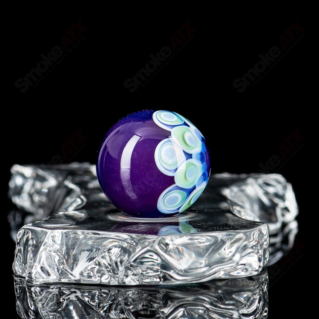 Clear glass marble with a single dot pattern on top, from Indo Glass, part of the Dot Stacked Top Mib collection.