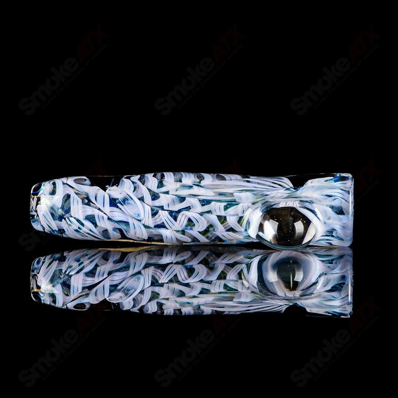 JMK Glass signed #8 I/O worked glass chillum with detailed design and craftsmanship, resting on a neutral background.