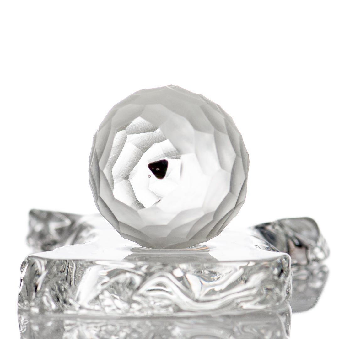 Faceted marble from Fatal Facets, glass marble with a smooth, polished surface and intricate faceted design.