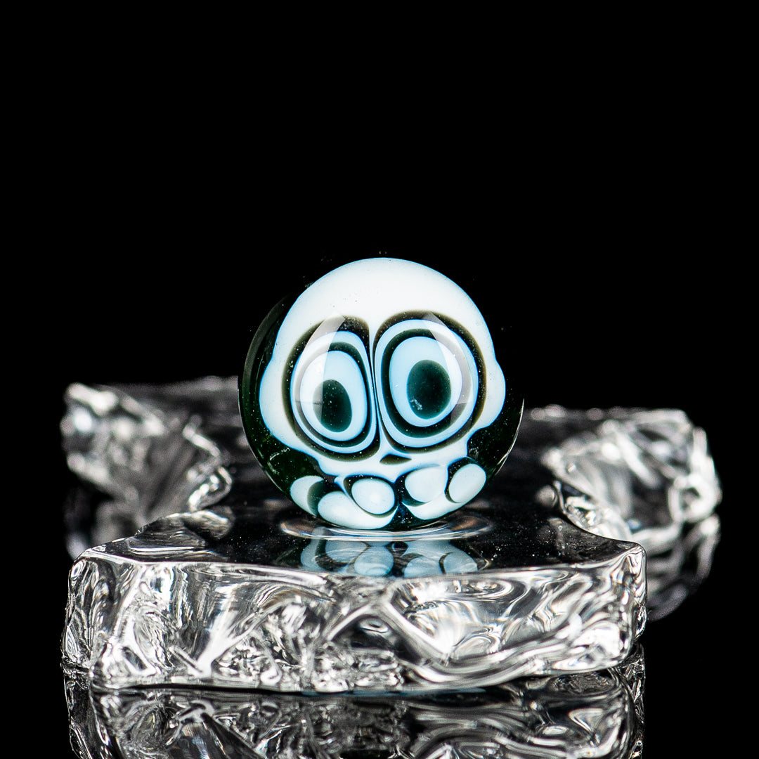 Indo Glass UV Dotstack Skull Marble featuring colorful dot patterns on a clear glass skull-shaped marble.
