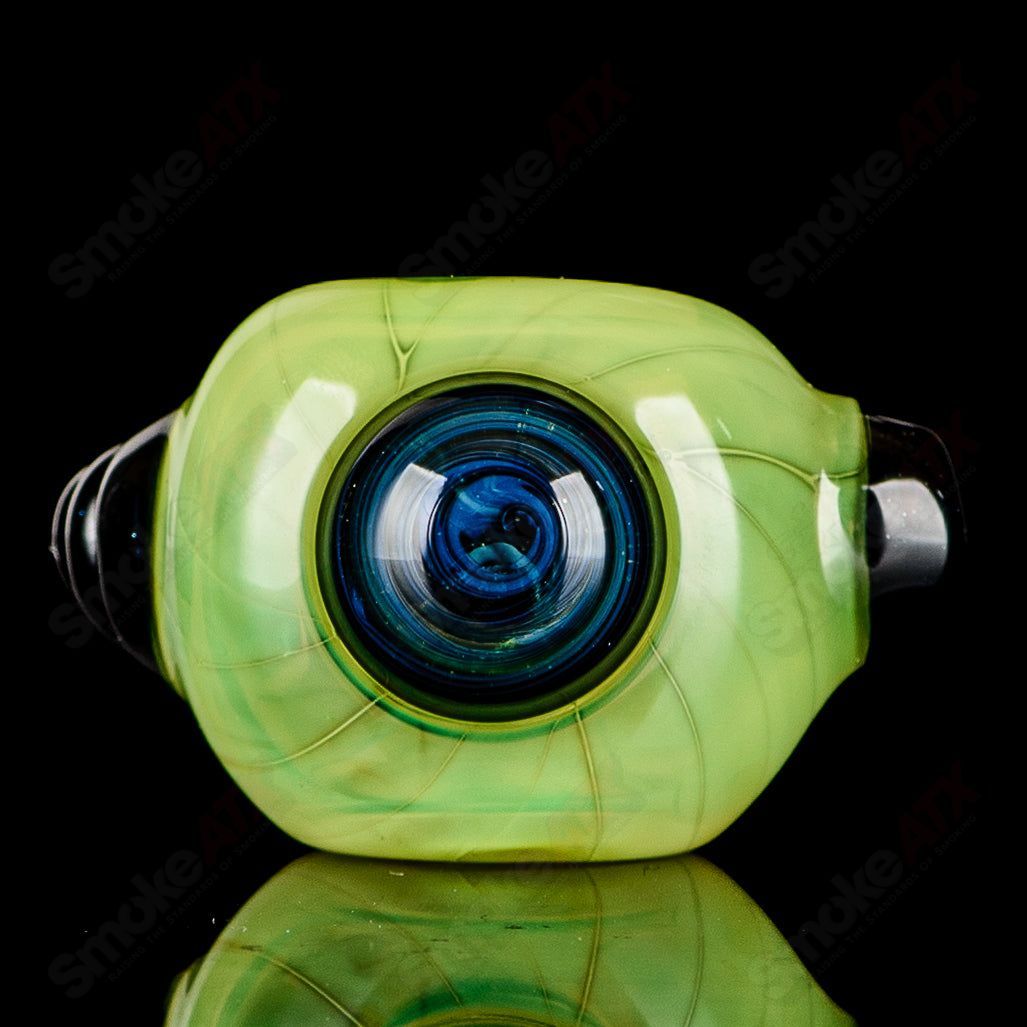 Transparent green glass spoon pipe with black horn accents, signed by JMK Glass, showcasing intricate craftsmanship and vibrant color.