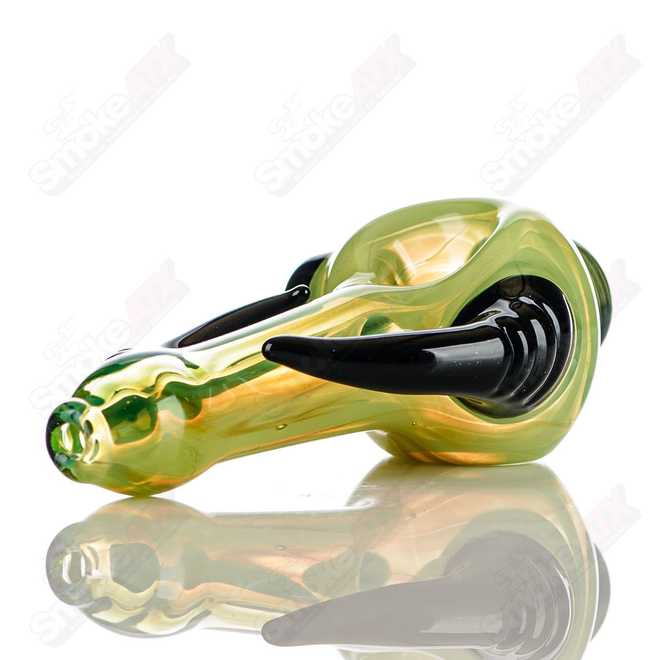 Transparent green glass spoon pipe with black horn accents, signed by JMK Glass, featuring a smooth, rounded bowl and intricate details.