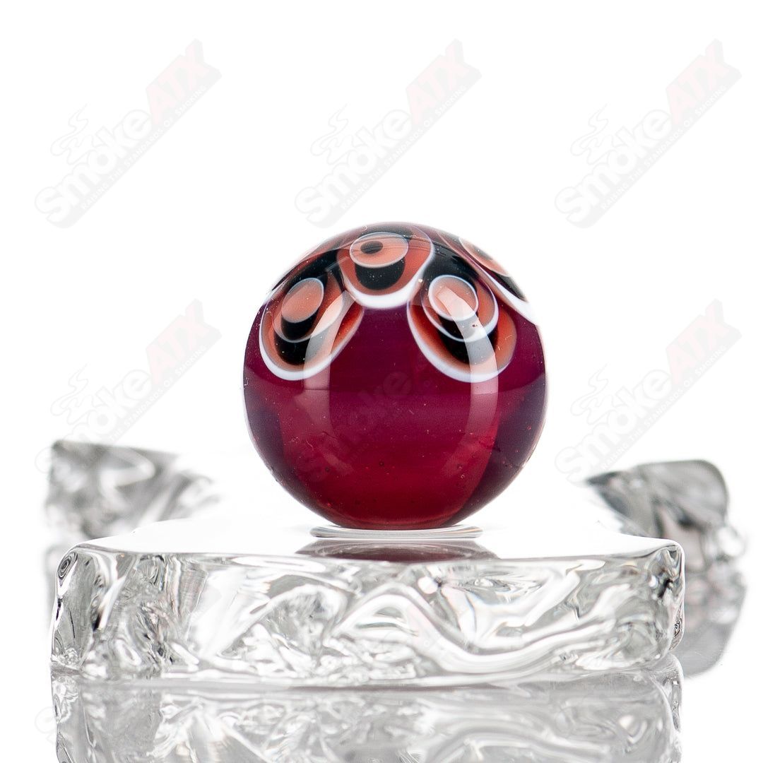 Red, black, and white dot stacked glass marbles from Indo Glass with colorful, patterned design.