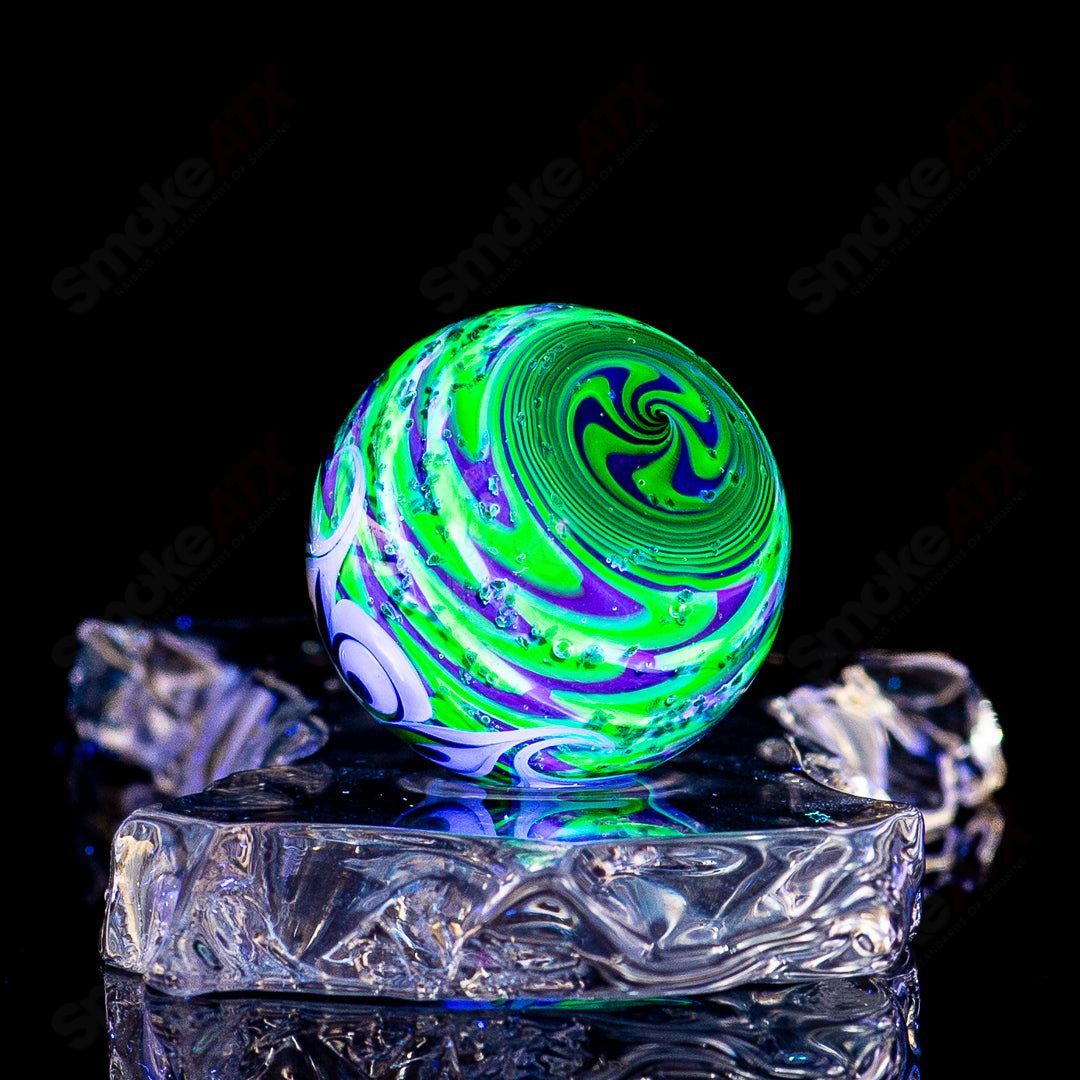 Black Magic UV Pinwheel Top marble by Indo Glass, vibrant glass marble with colorful pinwheel design, suitable for collection or play.