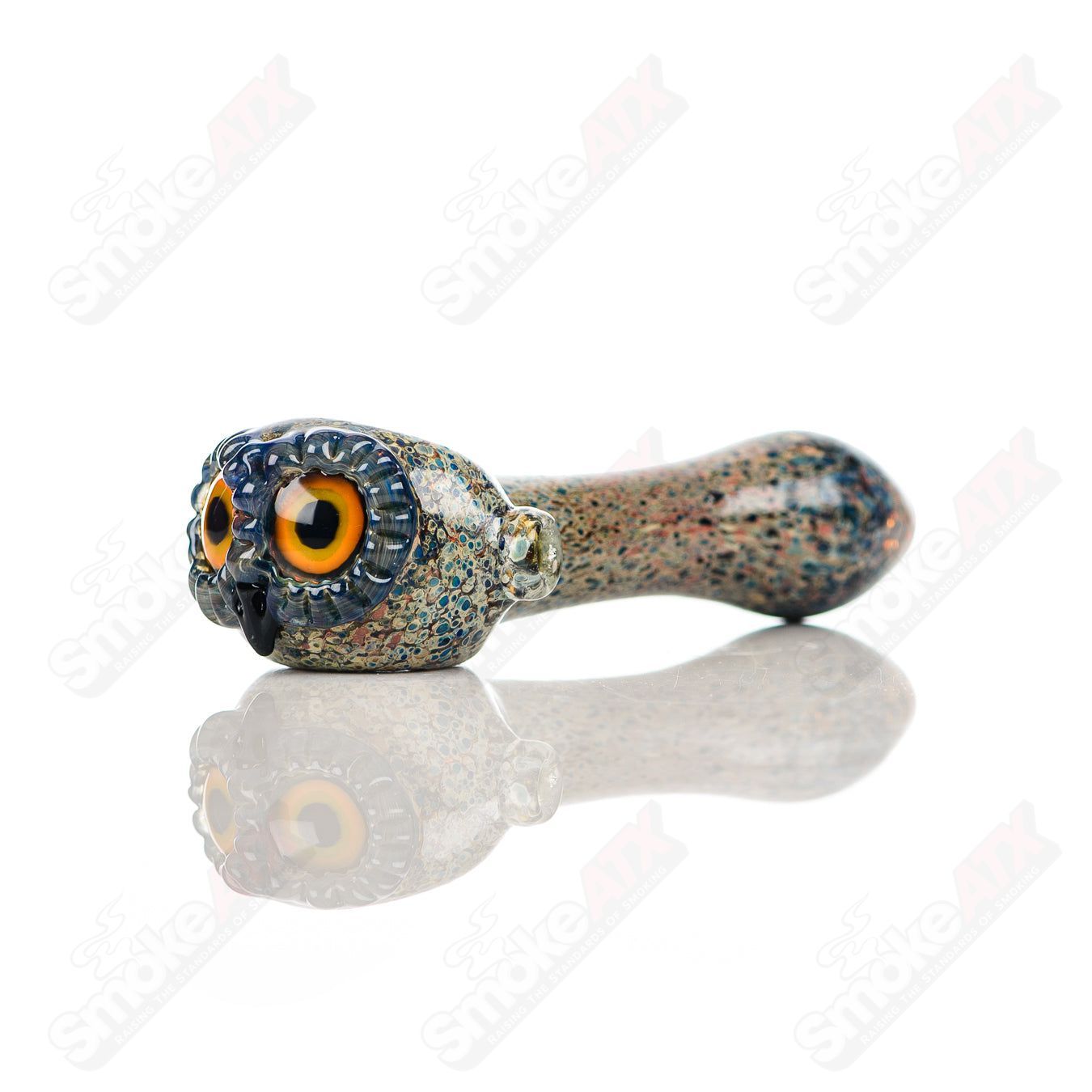 Glass pipe featuring a stone frit spotted owl design by Four Winds Flameworks, showcasing detailed glass artistry and vibrant colors.