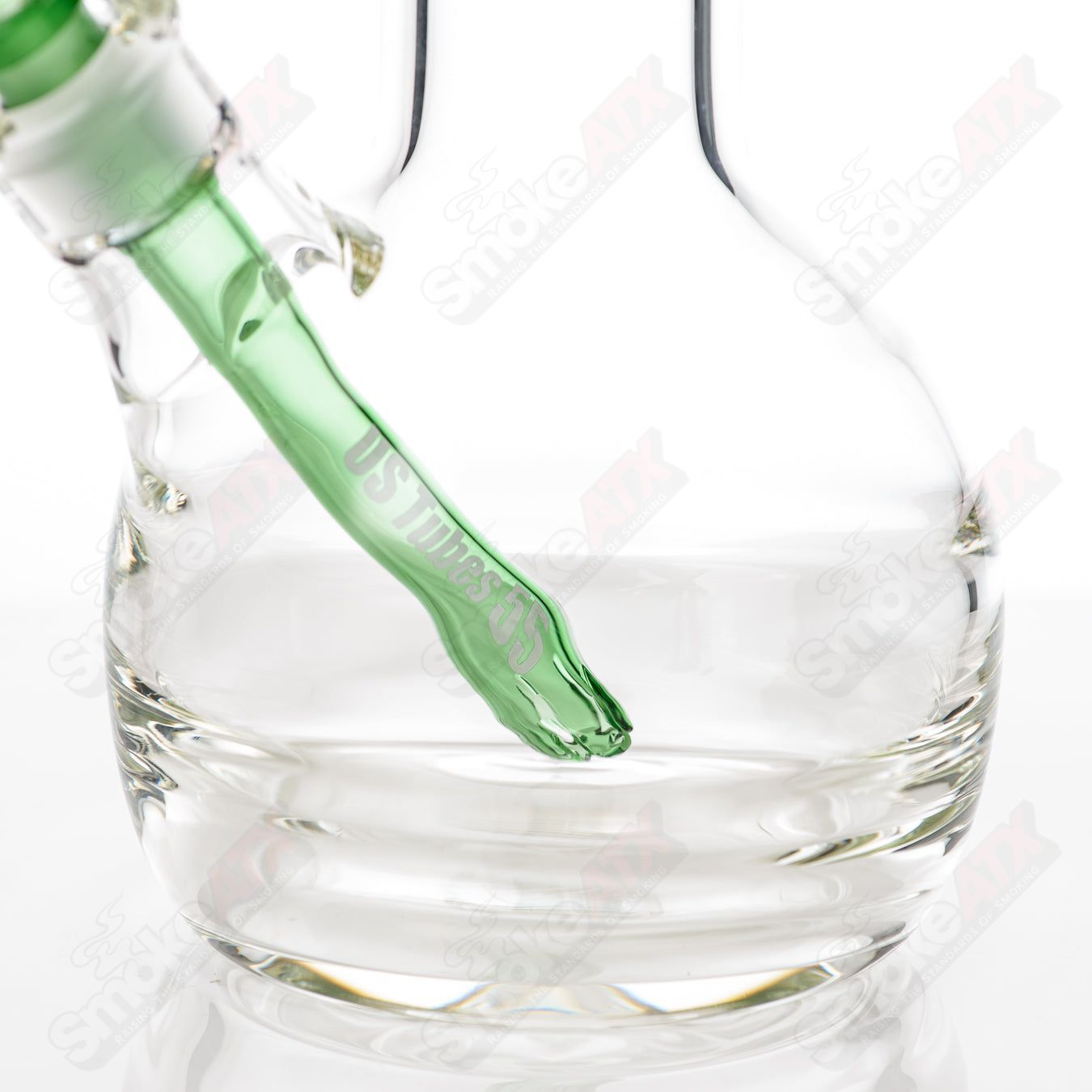 Glass US Tubes 17-inch beaker waterpipe with green decal and constriction design, featuring a clear glass body and sturdy base.